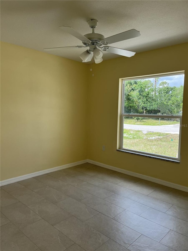 tiled empty room featuring ceiling fan