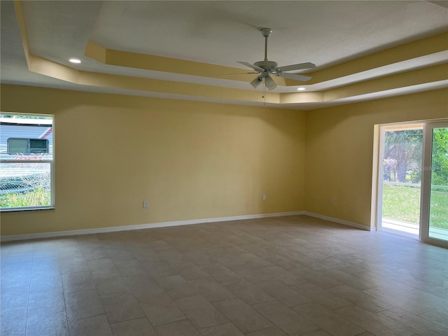 unfurnished room with ceiling fan and a tray ceiling