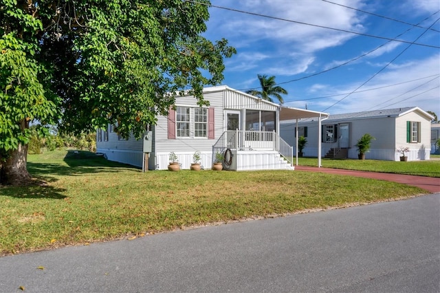 manufactured / mobile home featuring a carport and a front yard