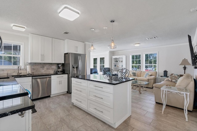 kitchen featuring a center island, white cabinets, decorative backsplash, pendant lighting, and appliances with stainless steel finishes