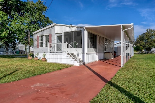 view of front of home featuring a front yard, a sunroom, and a carport