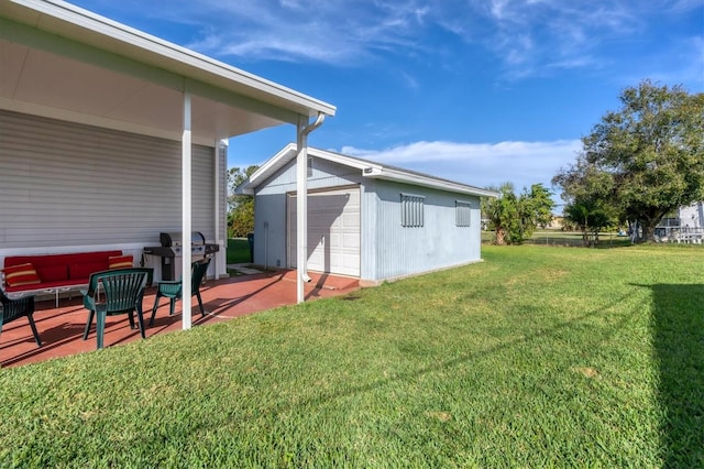 view of yard featuring a garage, an outbuilding, and a patio area