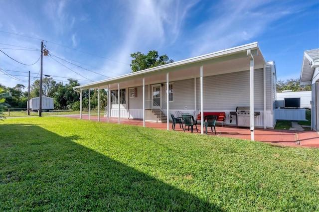 back of property with covered porch, a patio, and a yard