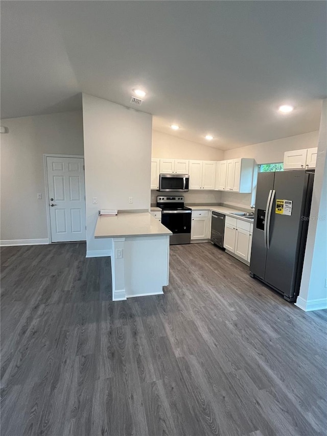 kitchen with white cabinets, dark wood-type flooring, stainless steel appliances, sink, and vaulted ceiling