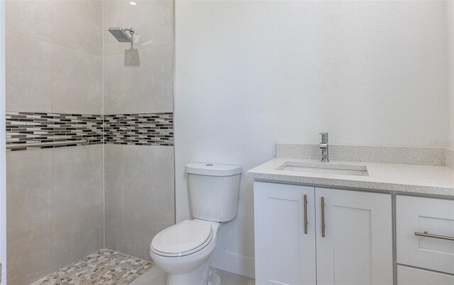 bathroom with tiled shower, toilet, and vanity