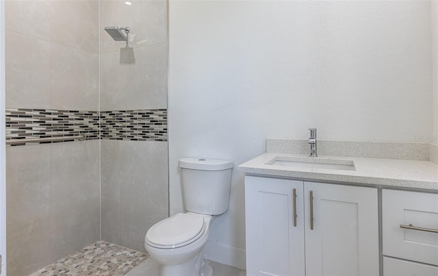 bathroom with vanity, a tile shower, and toilet