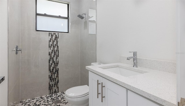 bathroom with tiled shower, tile patterned floors, toilet, and vanity