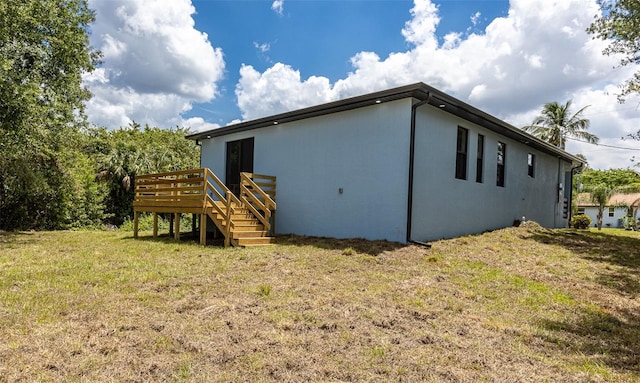 view of side of property featuring a deck and a lawn