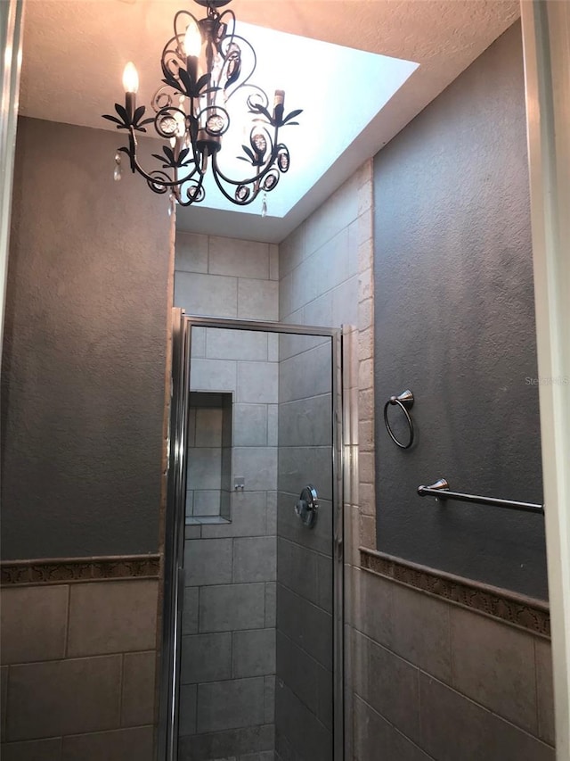 4127 Gardner Dr, Port Charlotte, FL 33952 - full bath featuring a stall shower, a wainscoted wall, tile walls, and an inviting chandelier