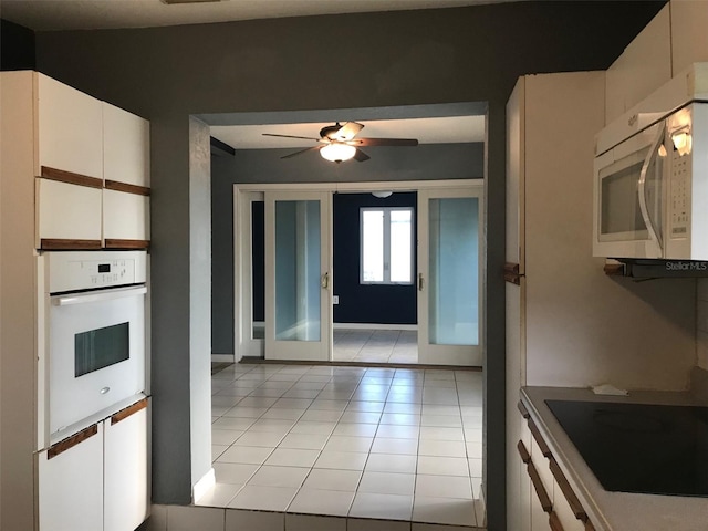 4127 Gardner Dr, Port Charlotte, FL 33952 - kitchen with light tile patterned floors, white appliances, white cabinetry, a ceiling fan, and french doors