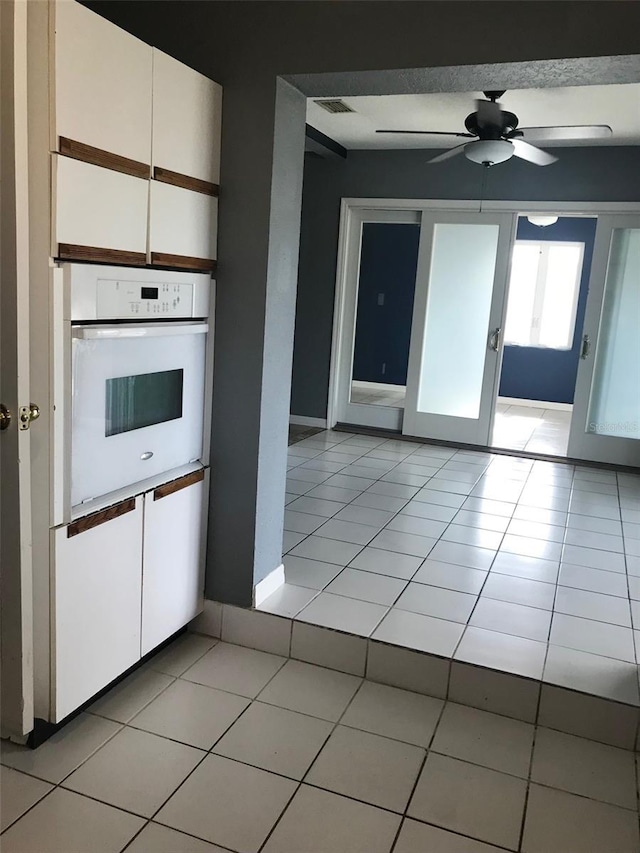 4127 Gardner Dr, Port Charlotte, FL 33952 - kitchen with white oven, light tile patterned flooring, and white cabinetry