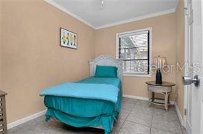 bedroom with ornamental molding and light tile patterned floors