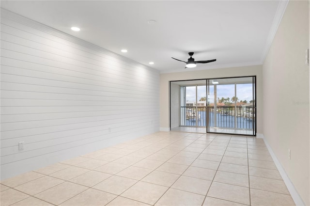 empty room with ornamental molding, a water view, ceiling fan, and light tile patterned floors