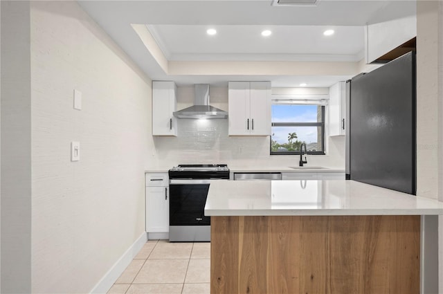 kitchen featuring appliances with stainless steel finishes, wall chimney exhaust hood, tasteful backsplash, and white cabinets