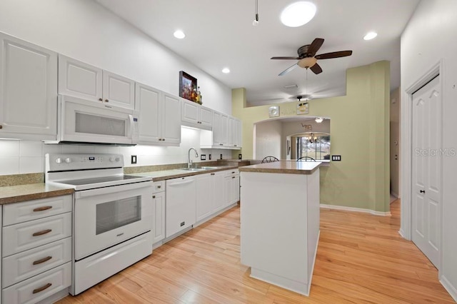 kitchen with white cabinets, white appliances, a kitchen island, and sink