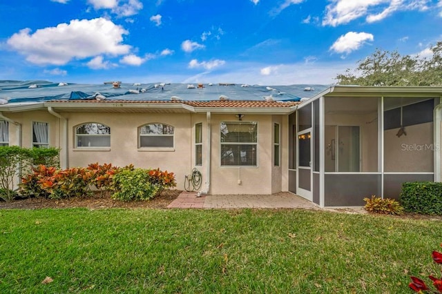 rear view of house featuring a sunroom and a lawn