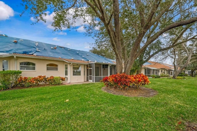 back of property featuring a sunroom and a yard