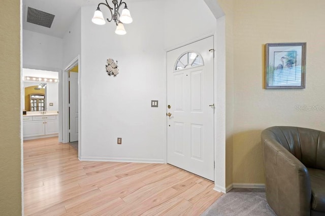 entrance foyer featuring a chandelier, vaulted ceiling, and light hardwood / wood-style flooring