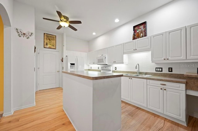 kitchen with sink, white cabinets, white appliances, and a kitchen island