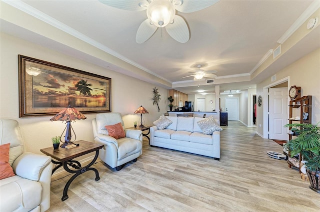 living room featuring ornamental molding, light hardwood / wood-style floors, and ceiling fan