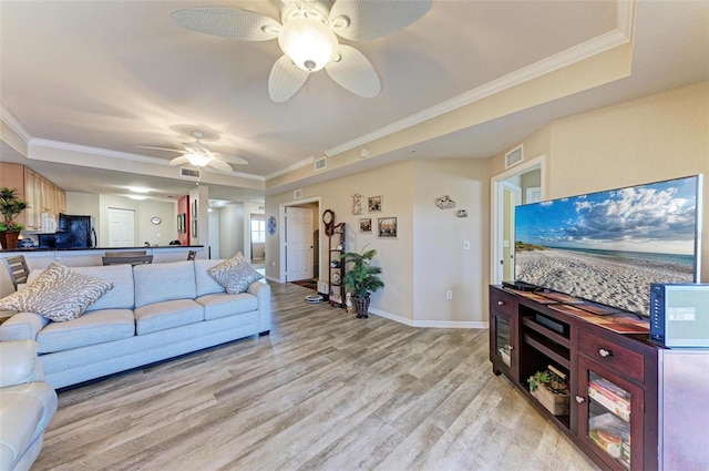 living room with ornamental molding, ceiling fan, light hardwood / wood-style floors, and a tray ceiling