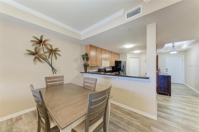 dining space featuring crown molding and light hardwood / wood-style flooring