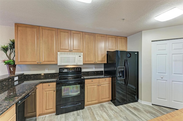 kitchen featuring a textured ceiling, black appliances, light hardwood / wood-style floors, and dark stone counters