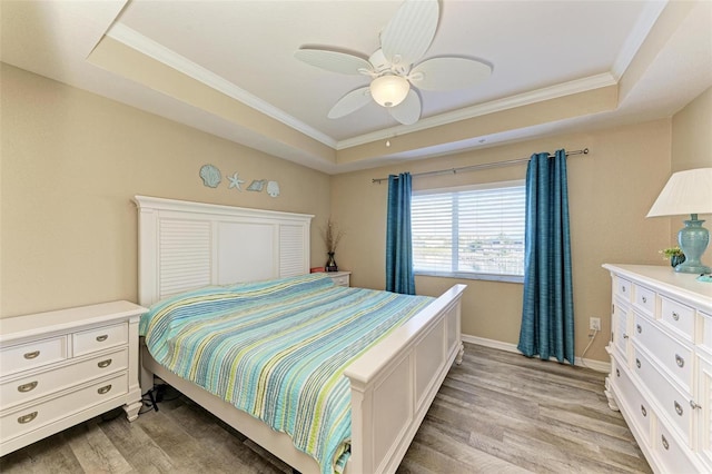 bedroom with crown molding, ceiling fan, a raised ceiling, and light wood-type flooring