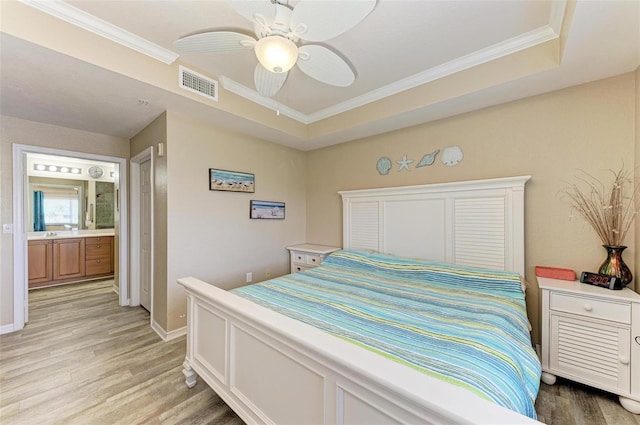 bedroom with ornamental molding, light hardwood / wood-style floors, and a raised ceiling