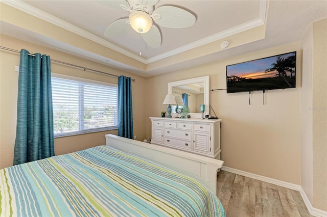 bedroom featuring crown molding, ceiling fan, a tray ceiling, and light wood-type flooring