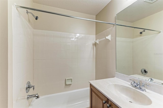 bathroom with tiled shower / bath, vanity, and a textured ceiling