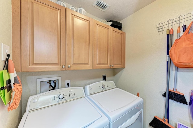 washroom with washing machine and dryer, cabinets, and a textured ceiling