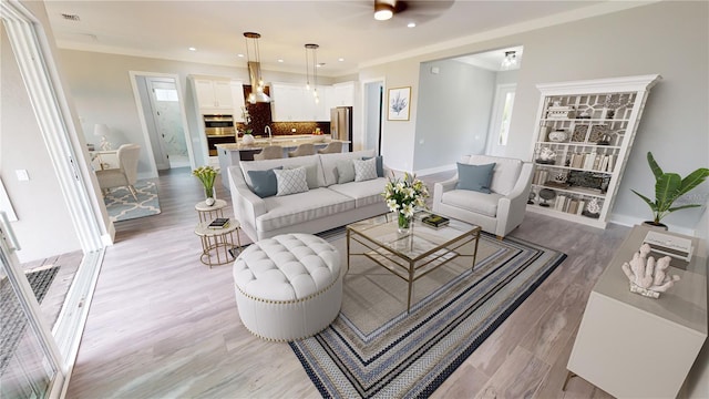 living room with ceiling fan, sink, crown molding, and light hardwood / wood-style floors