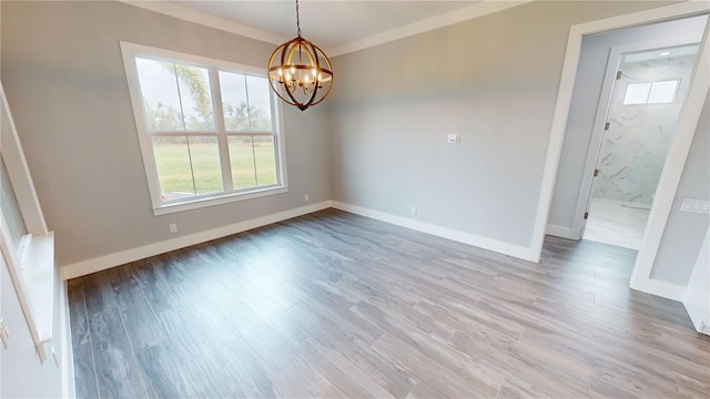 empty room with light wood-type flooring, crown molding, and an inviting chandelier