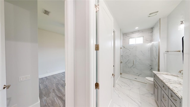 bathroom featuring toilet, vanity, and tiled shower