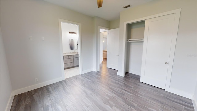 unfurnished bedroom featuring a closet, connected bathroom, light hardwood / wood-style flooring, and ceiling fan