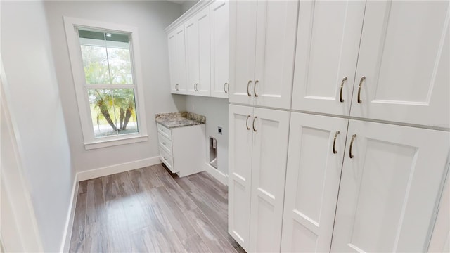 clothes washing area with cabinets, light hardwood / wood-style flooring, and hookup for an electric dryer