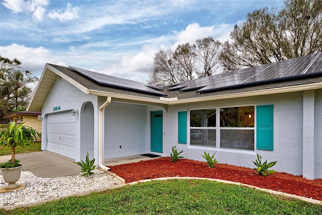 single story home featuring solar panels and a garage