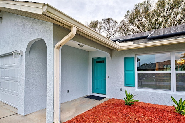 property entrance featuring a garage and solar panels