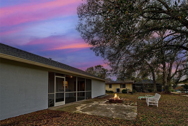 yard at dusk featuring an outdoor fire pit and a patio area