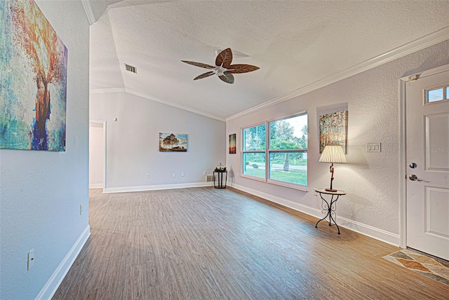 spare room featuring ceiling fan, a textured ceiling, ornamental molding, lofted ceiling, and light wood-type flooring