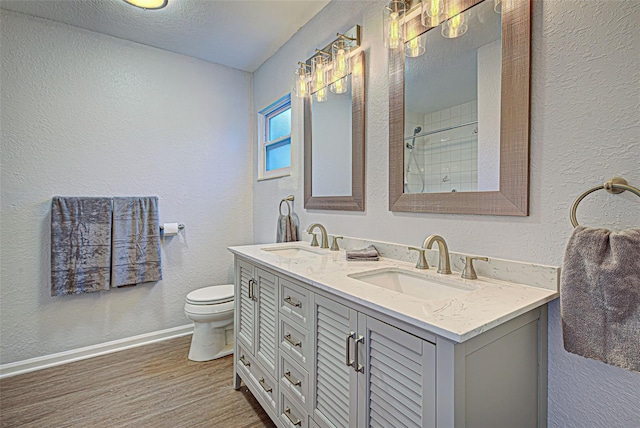 bathroom featuring toilet, dual sinks, a textured ceiling, large vanity, and hardwood / wood-style flooring