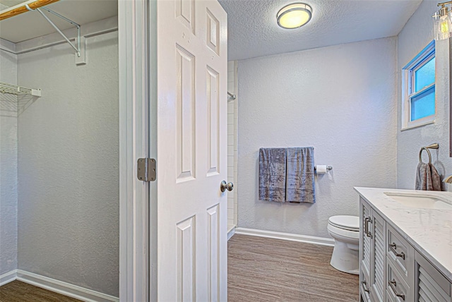 bathroom featuring vanity, hardwood / wood-style floors, a textured ceiling, and toilet