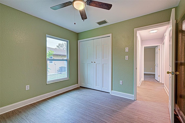 unfurnished bedroom featuring a closet, multiple windows, dark hardwood / wood-style floors, and ceiling fan