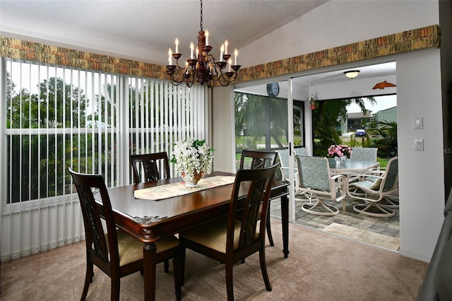 carpeted dining area with an inviting chandelier and lofted ceiling