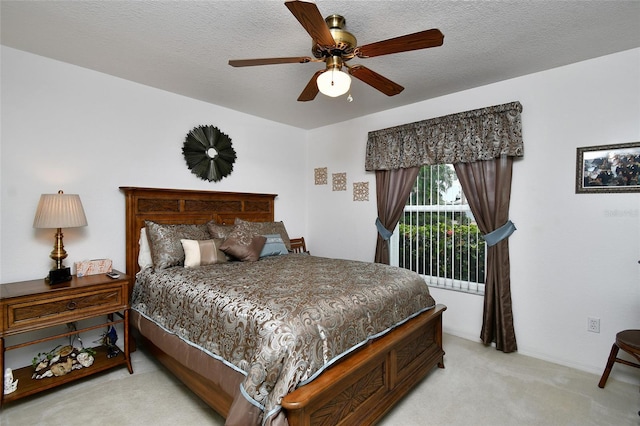 bedroom featuring a textured ceiling, light colored carpet, and ceiling fan