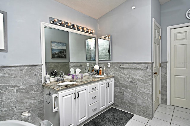 bathroom with tile floors, tile walls, and dual bowl vanity