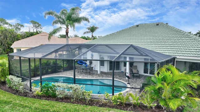 rear view of property featuring glass enclosure and a patio