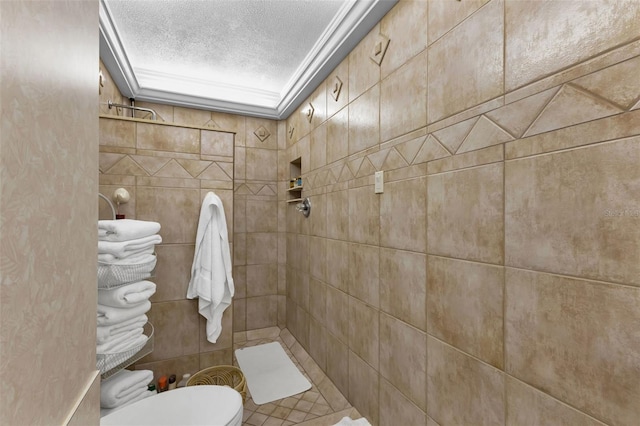 bathroom with toilet, crown molding, a textured ceiling, and a tile shower