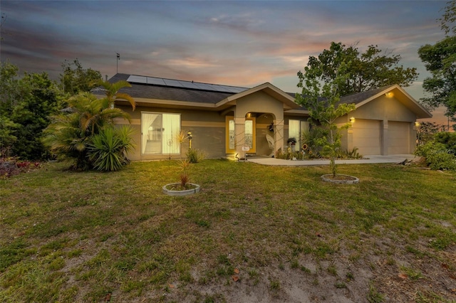 ranch-style house featuring solar panels, a yard, and a garage